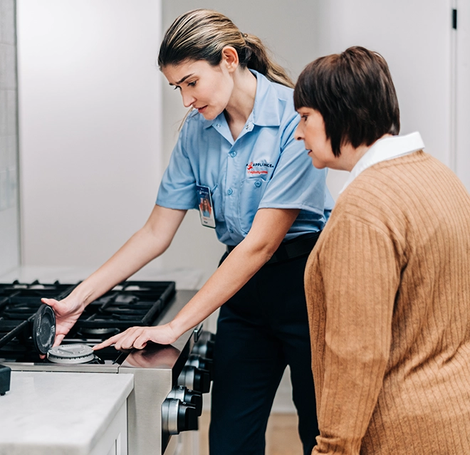 Mr. Appliance service professional examining top of stove with customer.