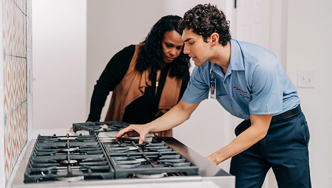 Mr. Appliance service professional showing a customer her repaired stove.