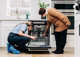 Mr. Appliance tech and customer looking inside a dishwasher.