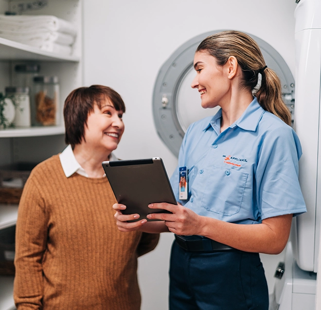 Mr. Appliance tech holding iPad while smiling at smiling customer.